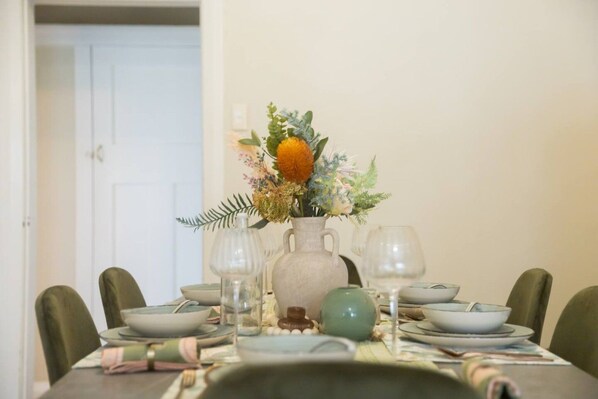 A dining table set with plates, bowls, and a vase of flowers.