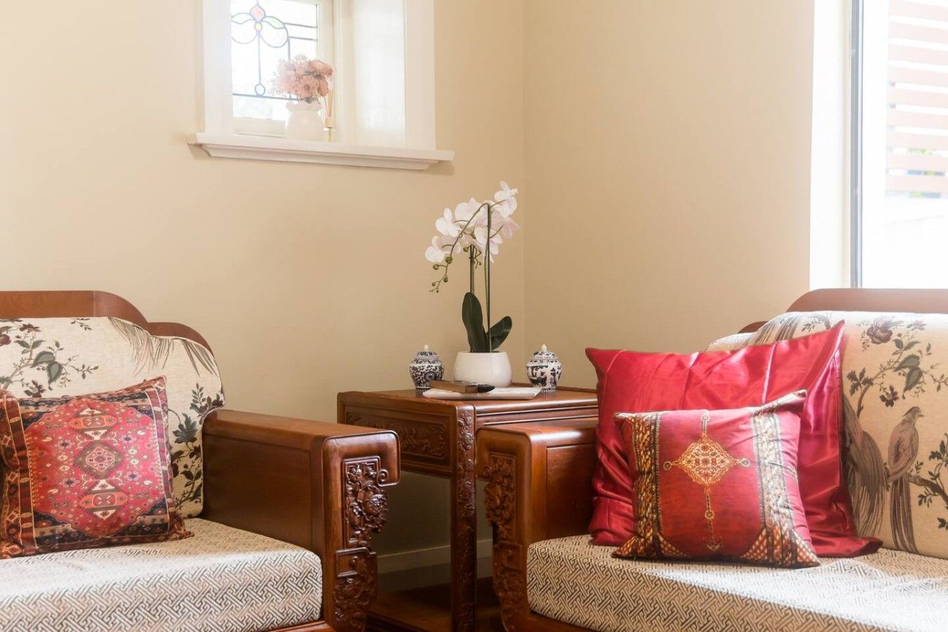 A cozy living room with two sofas, a wooden coffee table, and a window with a vase of flowers.