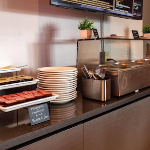 A buffet counter with various food items, plates, and utensils. - Estancias Vive MX el Marques (El Marques)