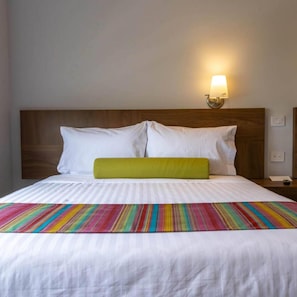 A hotel room with a bed, a nightstand, a lamp, and a wall socket. - Estancias Vive MX el Marques (El Marques)