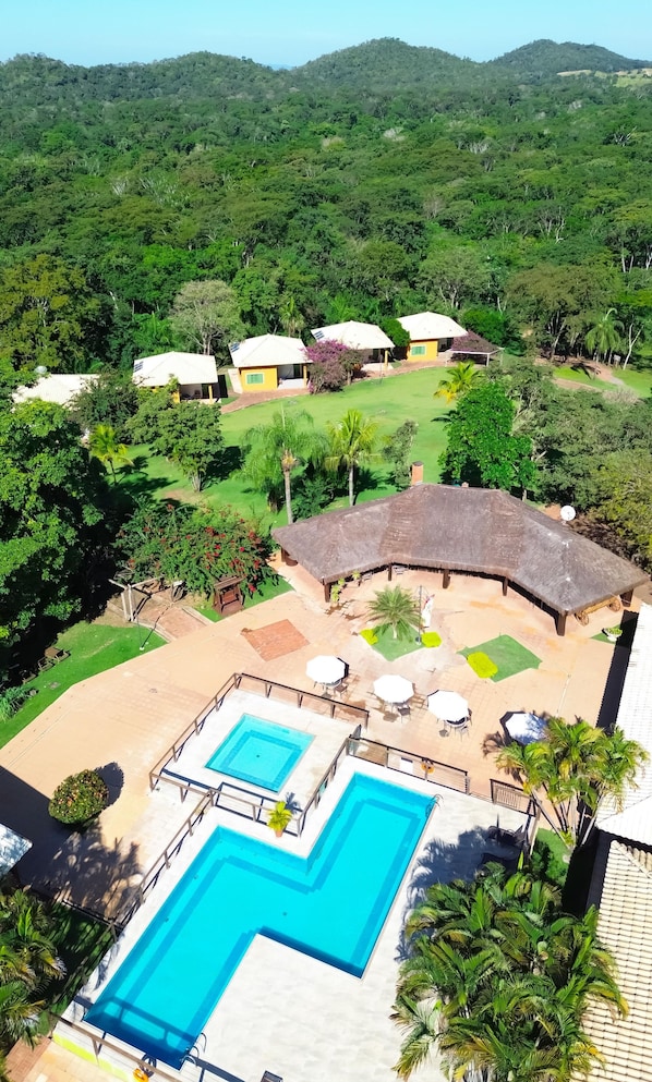 A resort with a pool, outdoor seating, and thatched-roof structures. - Hotel Fazenda Cachoeira Serra da Bodoquena (Bodoquena)