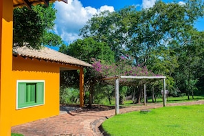 Un edificio amarillo con un camino de ladrillo que lleva a una zona cubierta con una pérgola.
