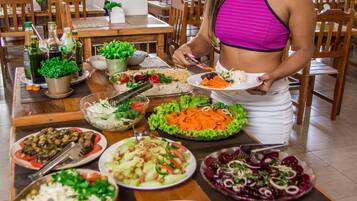 A buffet table with various dishes and a person serving food.