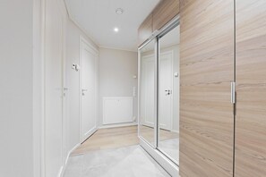 A hallway with a mirrored wardrobe, a radiator, and a door with a handle. - Spacious and modern holiday apartment in Levi (Levi)