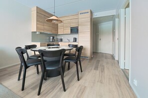 A modern kitchen with wooden cabinetry, a round dining table, and black chairs. - Spacious and modern holiday apartment in Levi (Levi)