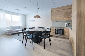 A modern kitchen with a round dining table, black chairs, and a built-in oven. - Spacious and modern holiday apartment in Levi (Levi)