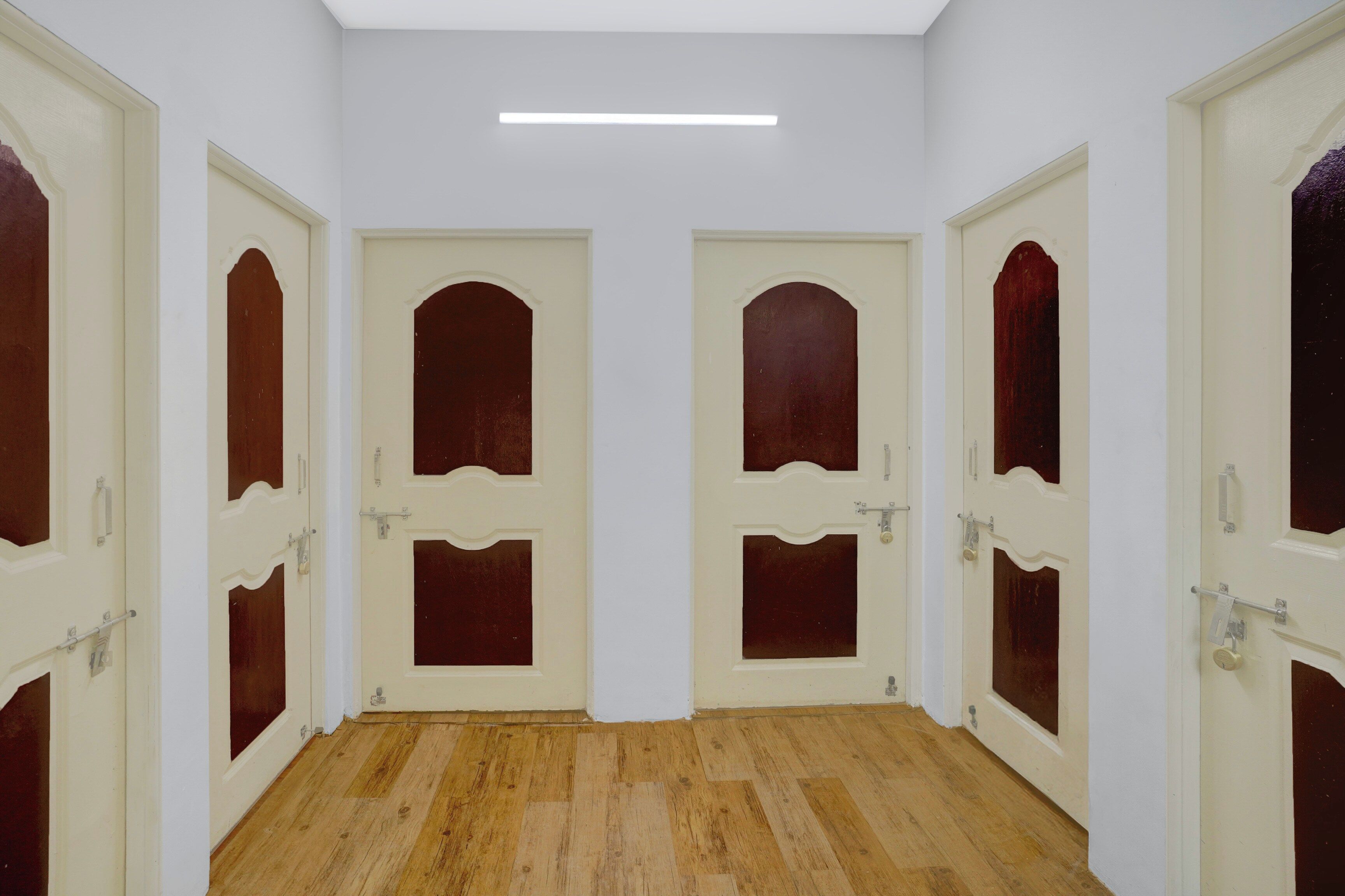 Un pasillo con cuatro puertas, cada una con un panel de madera y un pomo.