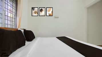 Habitación de hotel con una cama, ventana con vistas y tres cuadros en la pared.