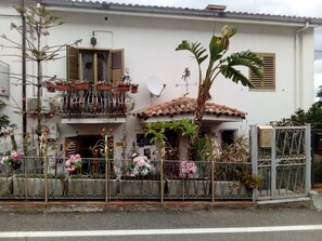 A two-story house with a balcony, a satellite dish, and a variety of potted plants. - New Listing (Taormina)