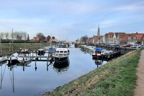 Un canal con barcos amarrados, un puente y edificios al fondo.