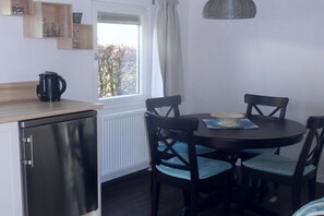 A compact kitchen with a refrigerator, a kettle, and a dining table with chairs. - Holiday apartment in Zoutelande with Wi-Fi (Zoutelande)