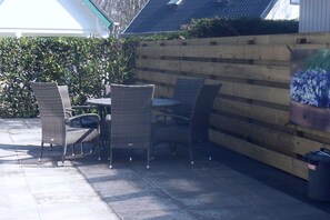 Un patio al aire libre con mobiliario de mimbre y una cerca de madera.