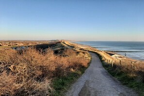 A coastal path leading to a beach with a clear view of the sea and distant buildings. - Holiday apartment in Zoutelande with Wi-Fi (Zoutelande)