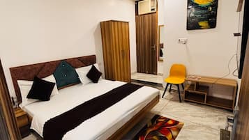 A bedroom with a bed, a desk, a chair, a wardrobe, and a ceiling fan.