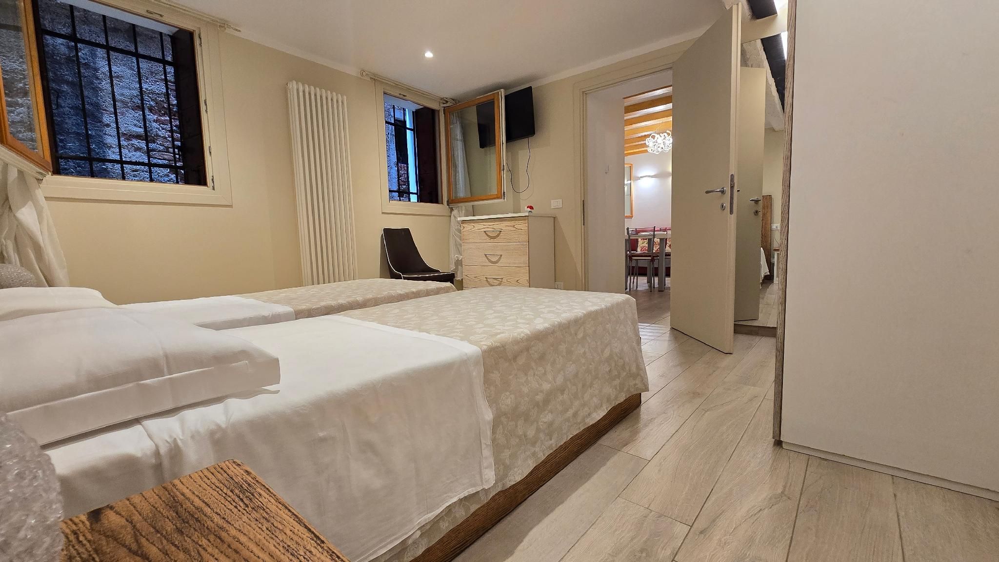 Un dormitorio con cama, una silla, cómoda y televisor.