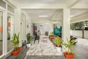 Una zona de recepción con disposición de asientos, plantas en macetas y vistas al exterior.