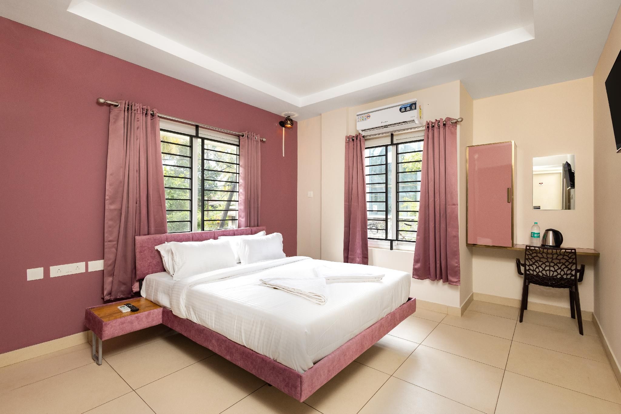 A bedroom with a bed, a desk, a chair, a mirror, and a window with curtains.