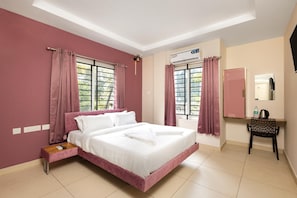 Un dormitorio con cama, escritorio, silla, espejo y ventana con cortinas.