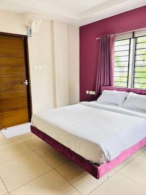 Un dormitorio con cama, ventana con cortinas, puerta y ventilador de techo.