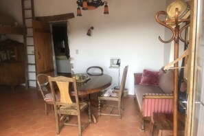A dining area with a round wooden table, two chairs, a bench, and a hanging light fixture. - Holiday home with 2 bedrooms (Lagorce, Ardèche)