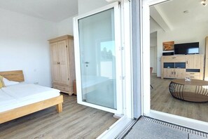 Een slaapkamer met een bed, een kledingkast en een schuifdeur naar een balkon.