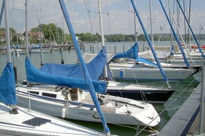 A marina with multiple sailboats docked, some covered with blue tarps. - B Dinkelbach Object 1 (Lindau)