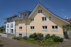 A multi-story residential building with a balcony, a flat roof, and a well-maintained garden. - B Dinkelbach Object 1 (Lindau)