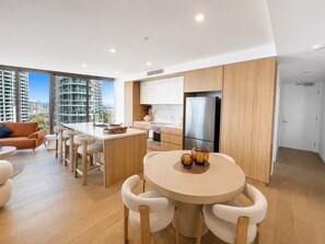 Cozinha moderna com ilha central, banquetas de bar e mesa de jantar com cadeiras.