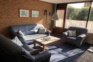 Ein Wohnzimmer mit Backsteinwand, einer Couch, einem Sessel und einem Couchtisch.