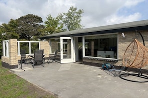 Een terras met een tafel en stoelen, een hangstoel en een fiets.