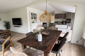 Ein moderner Essbereich mit einem dunklen Holztisch, gepolsterten Stühlen und einer hängenden Leuchte.
