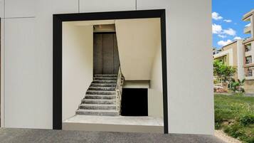 Una escalera conduce a un nivel superior, enmarcada por un diseño arquitectónico minimalista con fachada plana y borde negro.