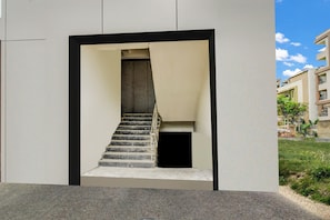 Una escalera conduce a un nivel superior, enmarcada por un diseño arquitectónico minimalista con fachada plana y borde negro.