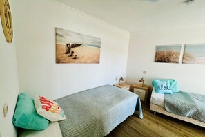 A bedroom with two beds, a nightstand, a lamp, and a painting on the wall. - Apartment in Julianadorp with swimming pool (Julianadorp)