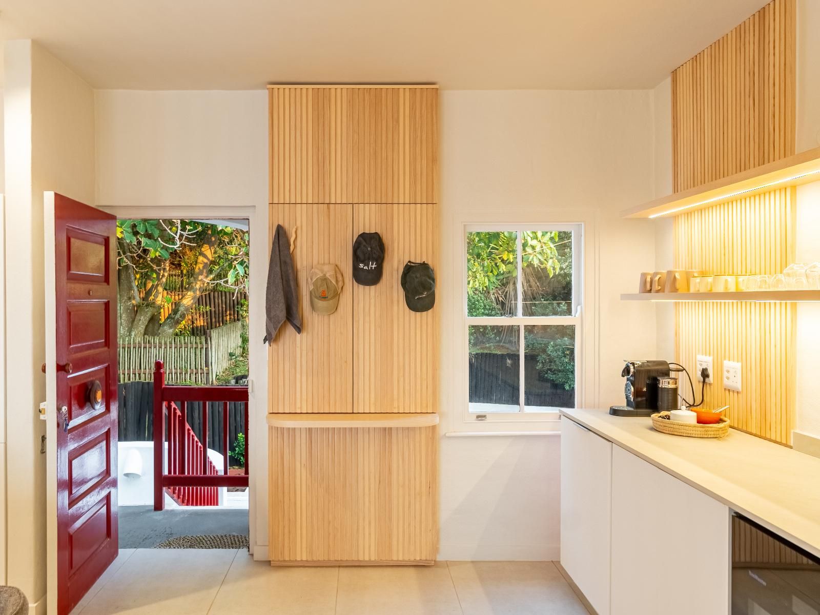 Una cocina moderna con armarios de madera, una puerta roja y un ventanal con vistas a un jardín.