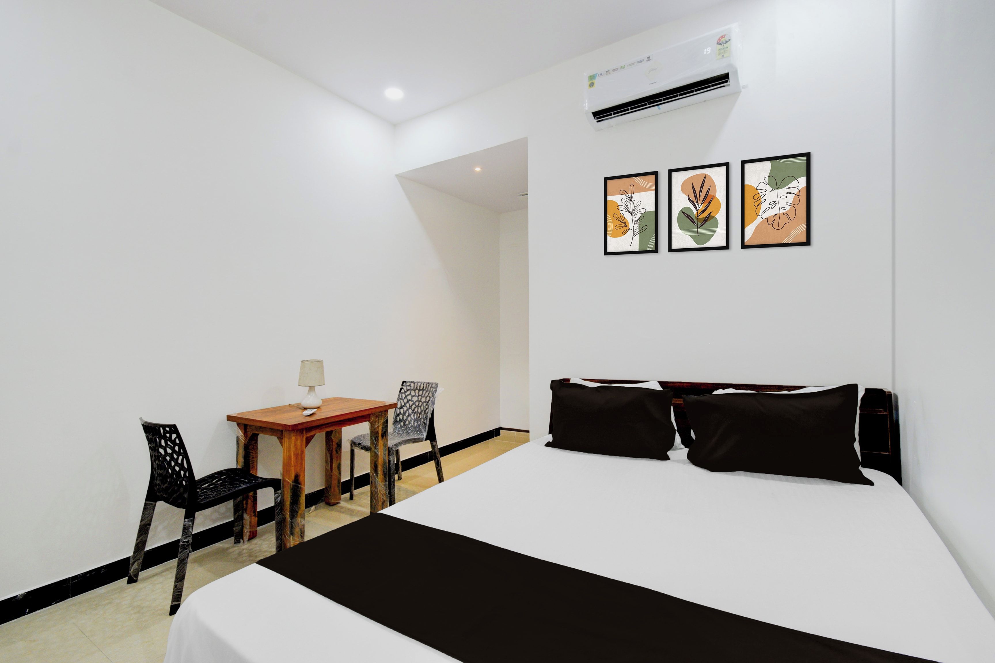 Una habitación de hotel con una cama, un escritorio, dos sillas y tres obras de arte colgadas en la pared.