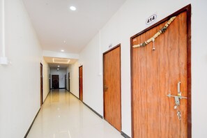 A corridor with two wooden doors, each marked with a number. The corridor has a glossy floor and is well-lit with ceiling lights.