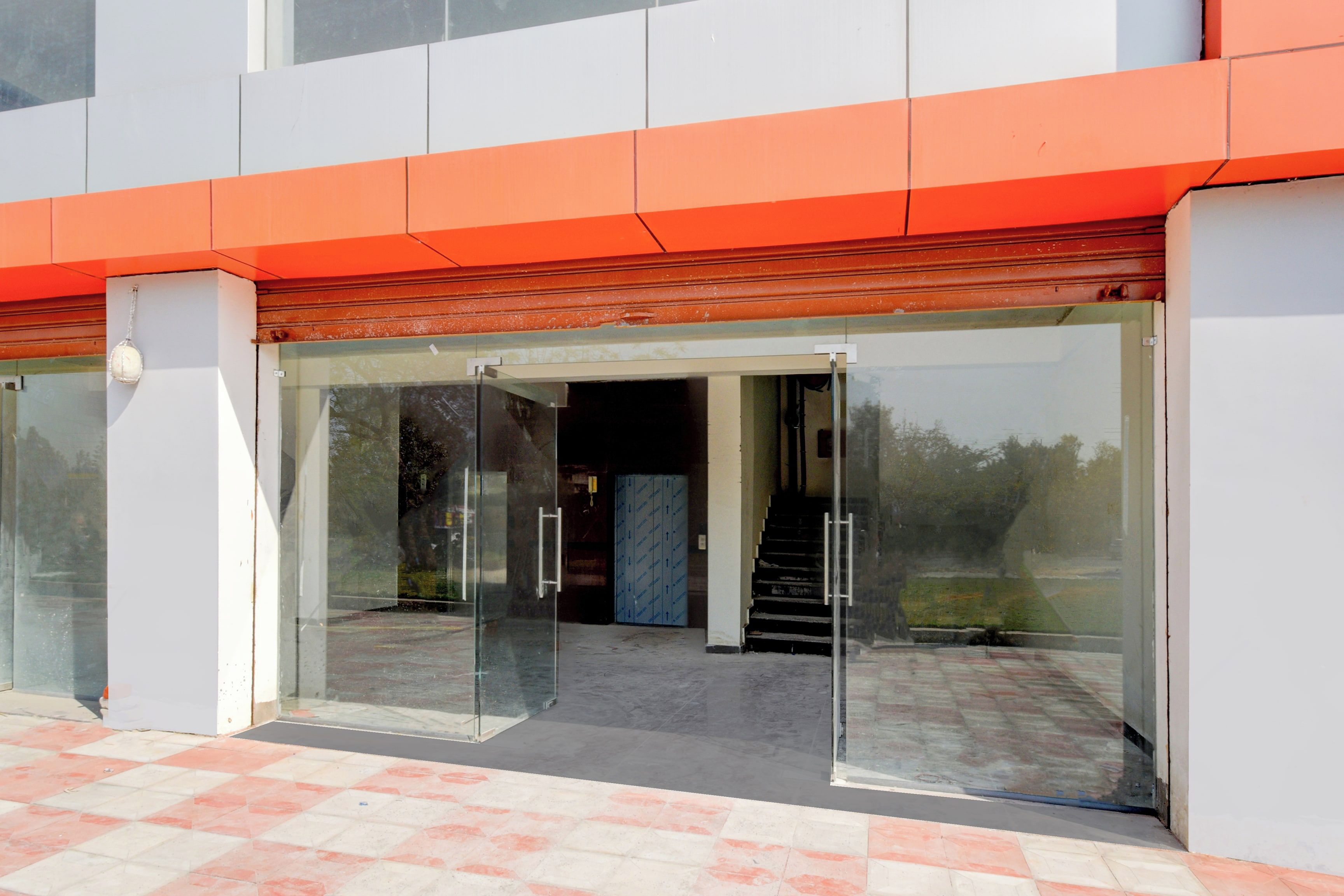 Entrada de un edificio con puerta de vidrio y un conjunto de escalones que conducen al interior.