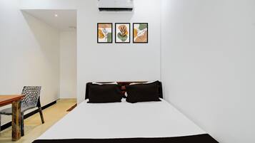 Una habitación de hotel con una cama, una silla y tres cuadros enmarcados en la pared.