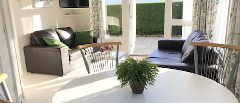 A living room with a sofa, a dining table, and a potted plant.