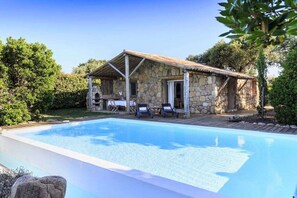 Ein Gebäude aus Stein mit Pool, Sitzgelegenheiten im Freien und einer überdachten Terrasse.