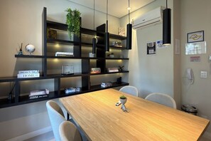 Een moderne kantoorruimte met een houten vergadertafel, zwarte open planken en een potplant.