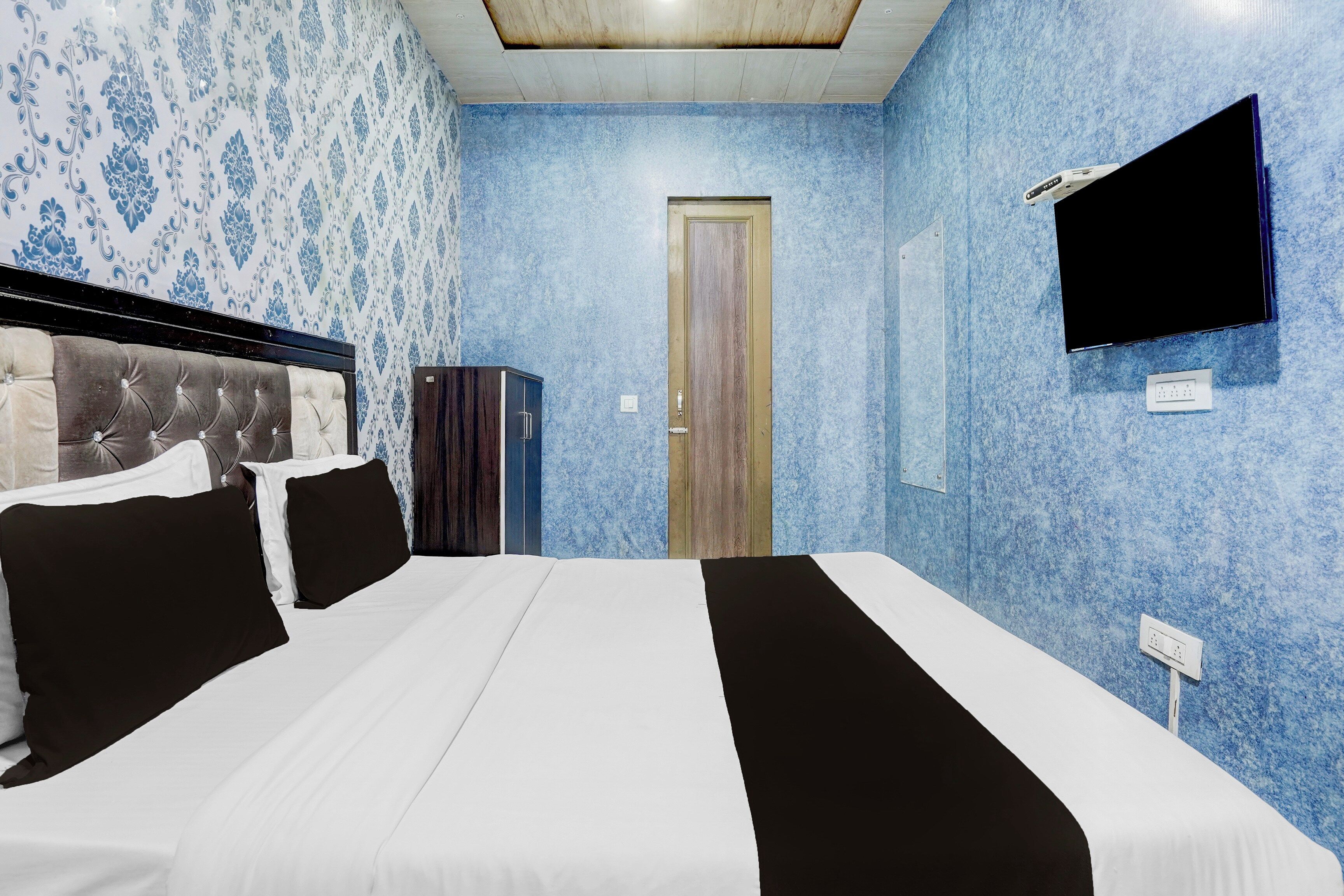 Una habitación de hotel con cama, armario, televisor y puerta.