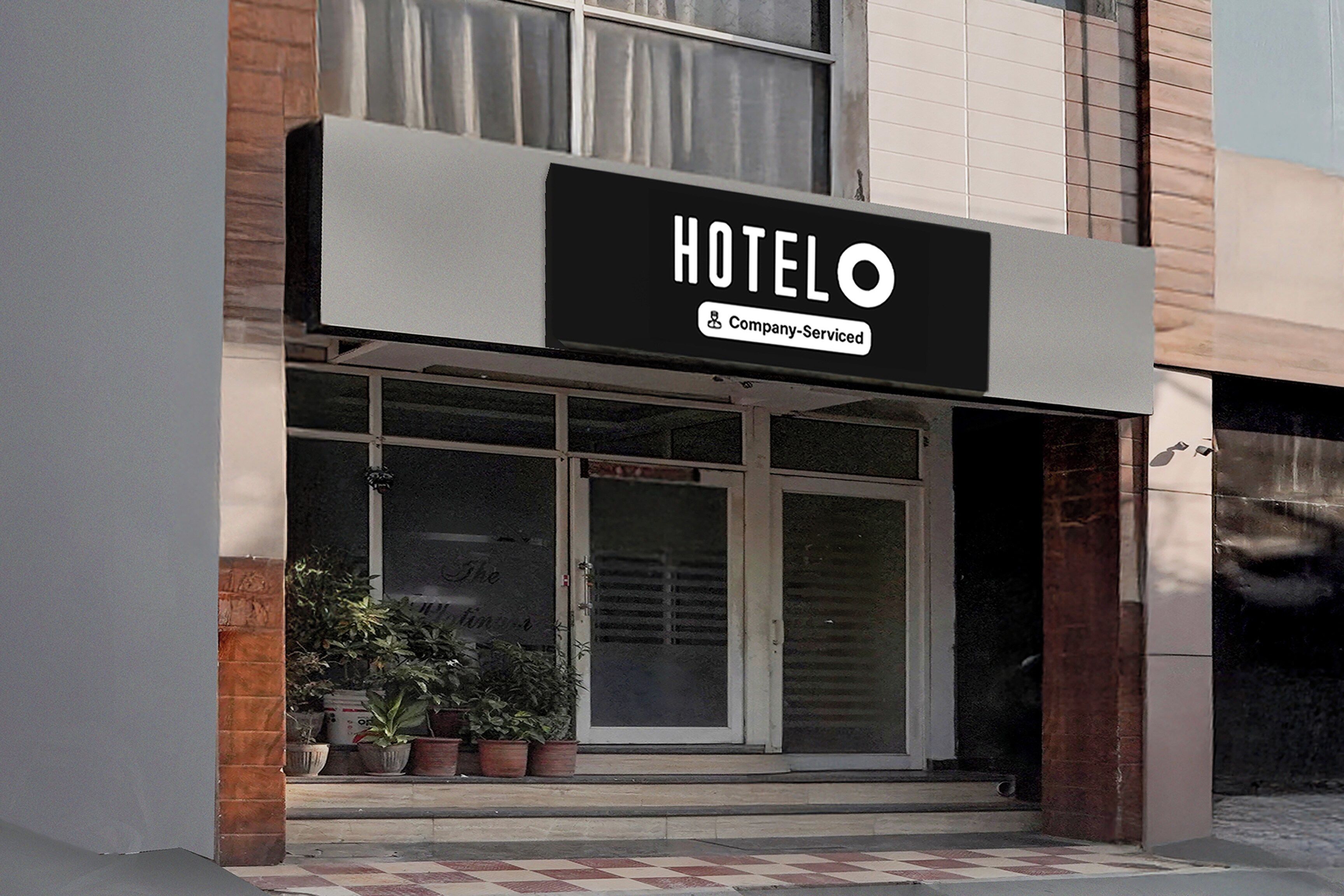 Entrada de un hotel con un letrero que dice 'HOTEL Company-Serviced'.