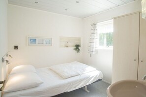 A bedroom with a single bed, a bedside table, a mirror, and a window with curtains. - Holiday apartment with 1 bedroom (Zoutelande)