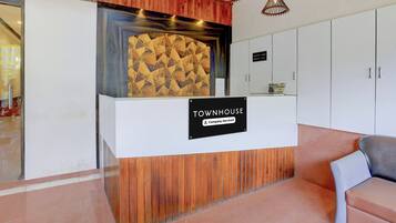 A reception desk with a 'TOWNHOUSE' sign, wooden paneling, and a check-in/out sign.