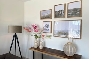 A wall with framed pictures, a sign saying 'GOOD VIBES ONLY', and a vase with flowers on a shelf. - Villa in Vrouwenpolder with Wifi (Vrouwenpolder)