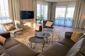 Un salon moderne comprenant un canapé, une table basse et un téléviseur fixé au mur.