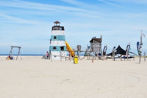 Une plage avec un phare, une structure en bois et une tente.