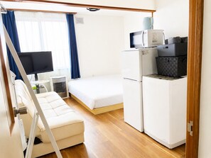 A compact hotel room with a bed, a small kitchenette, a television, and a window with curtains. - New Listing (小樽市)